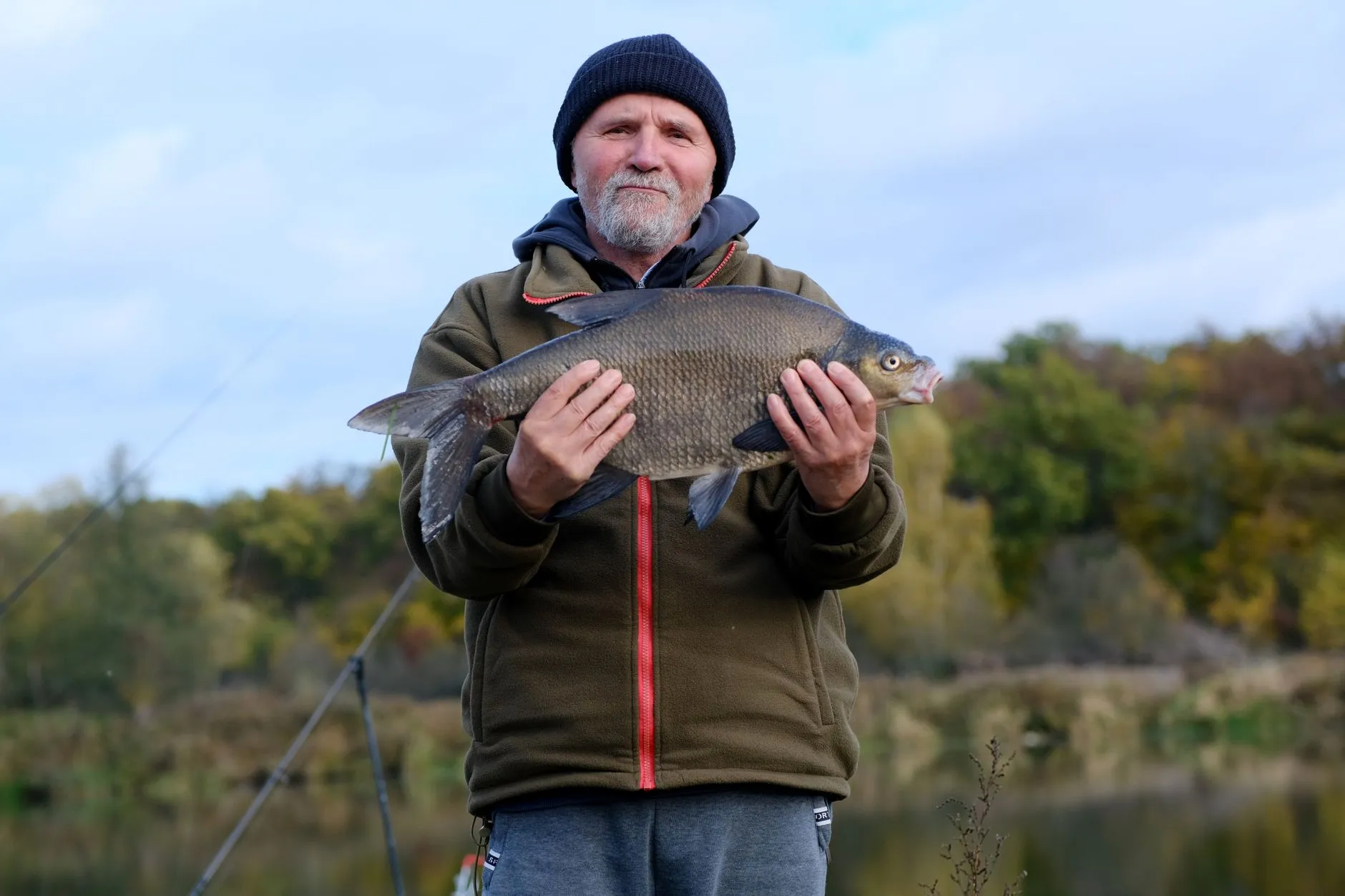 Ein Angler hält einen hochrückigen, bronzefarbenen Fisch dicht über dem Wasser.