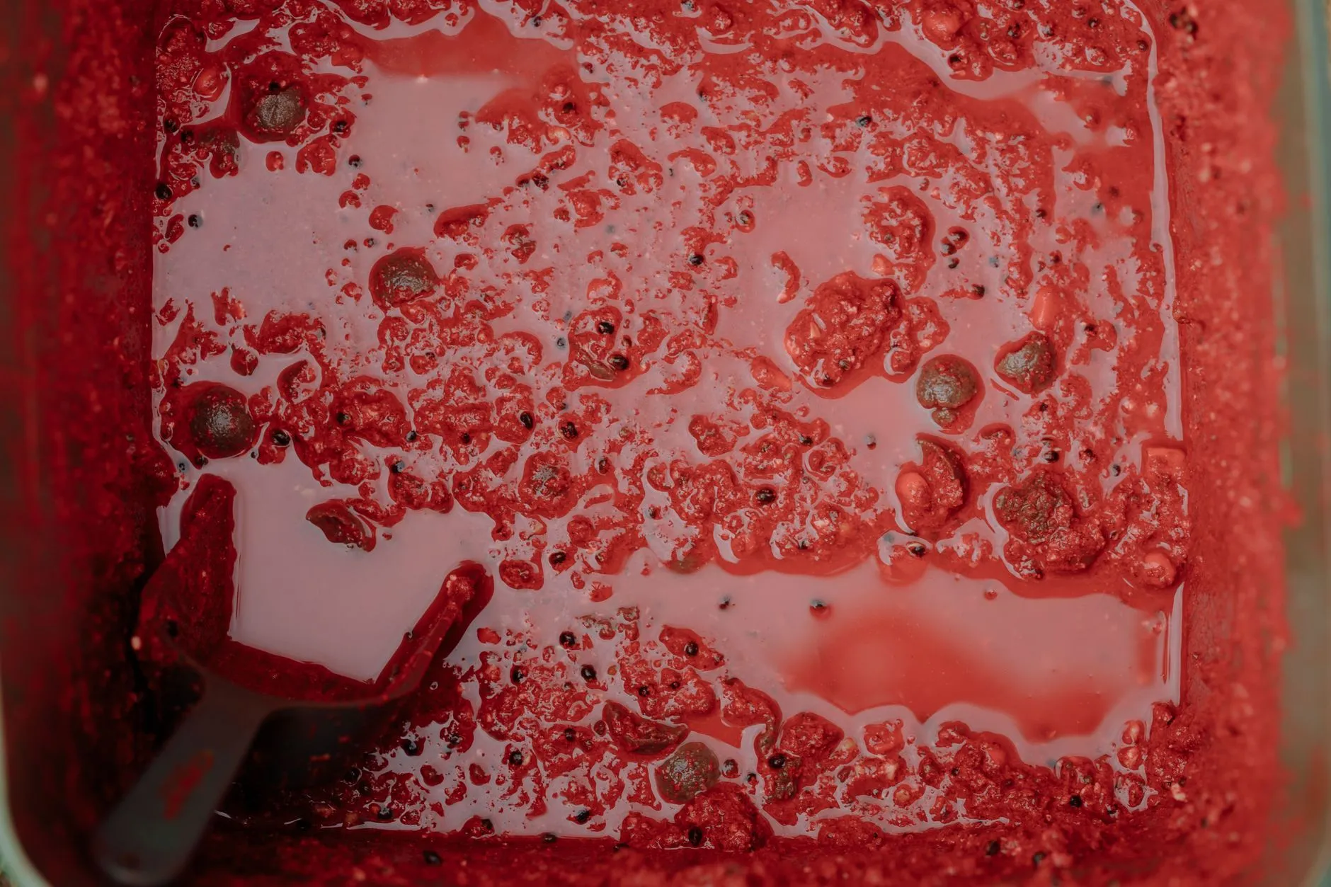 Rote Ködermasse mit einer Schaufel in einem Behälter